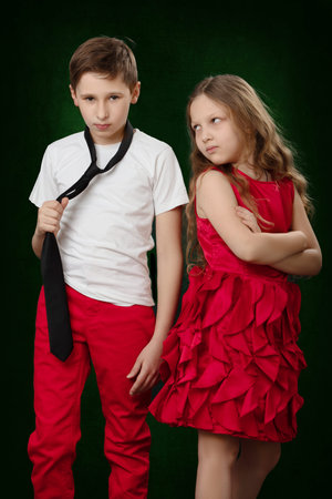 The girl looks reproachfully at the boy who angrily holds the tie. Childish grievances.の写真素材