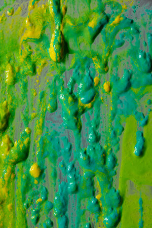 Bright green and yellow paint splashes cover the surface. The paint is thick and has a glossy...