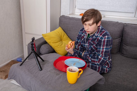 Boy eats pizza at home while filming himself.の写真素材