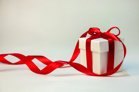 Christmas Gift in White Box with Red Ribbon on Light Background. New Year Holiday Composition. Copy Space For Your Textの写真素材