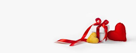 Concept Valentine's Day. Red Soft Toy Heart and White Gift Box with Red Ribbon and Little Cookie in the Shape of Heart on Light Background. Banner. Copy Space of Your Text.の写真素材