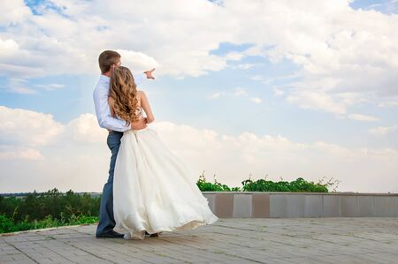 Wedding Day. Beautiful Bride in the Arms of the Groom on Sky Backgroundの写真素材