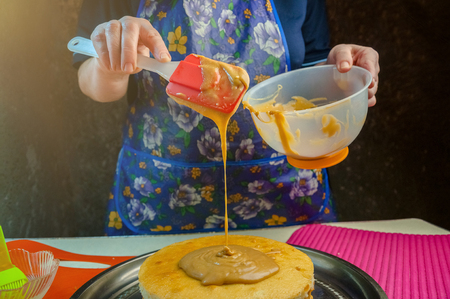 Baking Ingredients and Utensils for Cooking Sponge Cake. Process Cooking Sponge Cake. Woman Puts the Cream on the Cakes.の写真素材