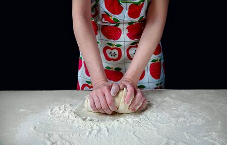 Woman Hands Kneads the Dough with White Flour on the Kitchen Table on a Dark Backgroundの写真素材