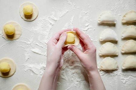 Woman Hands Sculpts Dumplings with Potatoes on White Background. Traditional Ukrainian Foodの写真素材