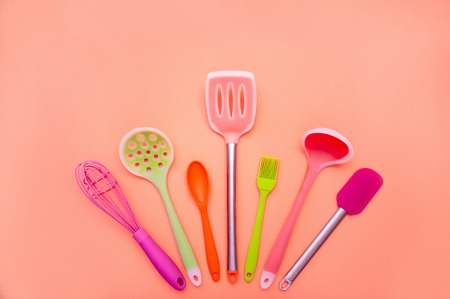 Various Colored Silicone Kitchen Utensils on Coral Background. Copy Space For Your Textの写真素材