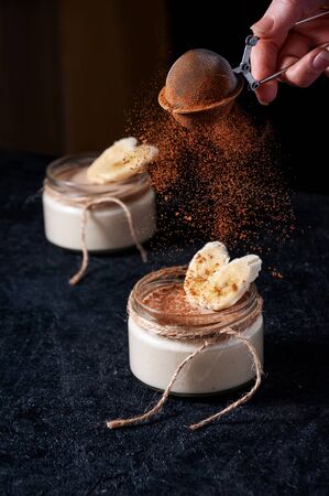 Healthy Banana Mousse or Pudding with Sifting Cocoa on Dark Backgroundの写真素材
