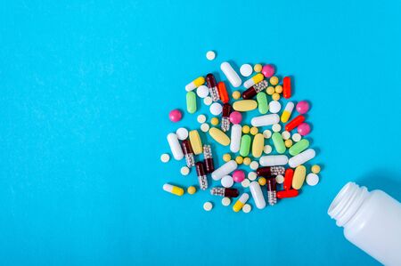 Colorful Assorted Pharmaceutical Pills, Tablets, Capsules and Bottle on Blue Background. Copy Space