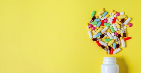 Colorful Assorted Pharmaceutical Pills, Tablets, Capsules and Bottle on Yellow Background. Bannerの写真素材