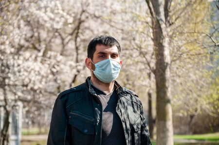 COVID-19. Young Man in Protective Sterile Medical Face Mask Outdoors. Coronavirus Concept.の写真素材