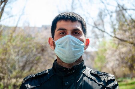 COVID-19. Young Man in Protective Sterile Medical Face Mask Outdoors. Coronavirus Concept.の写真素材