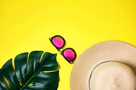 Straw hat, pink sunglasses and palm leaf on yellow background. Creative minimal concept. Top view Flat layの写真素材