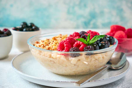 Close-up oatmeal with different berries and crushed nuts in a glass bowl. Healthy balanced foodの写真素材