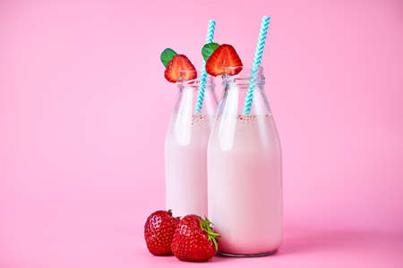 Close-up strawberry smoothie or milkshake in glass jar with berries on pink background. Summer drinkの写真素材