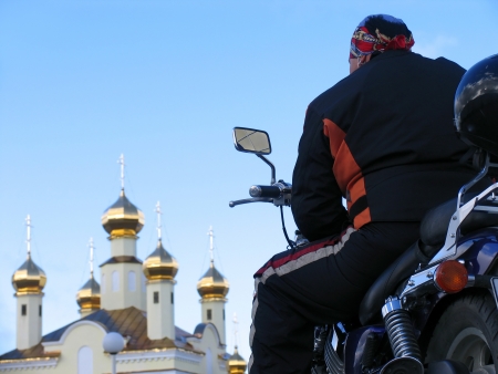 Classical biker looks at church temple  Nadym, Russia のeditorial素材