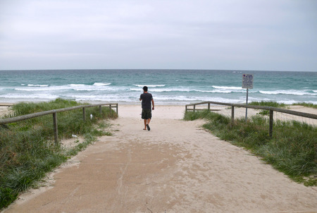 Paradise Surfers, Golden Coast, Queensland Australia - 5 November 2007: The beach, the coast of the Pacific Ocean. A man walking towards the water.のeditorial素材