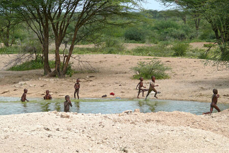 ISIOLO, KENYA - 28 NOVEMBER 2008: Unknown small Kenyan children bathe in the river in Isiolo, Kenya - 28 November 2008. River and trees around.のeditorial素材