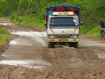 KIBITI, TANZANIA - DESEMBER 2, 2008: a Truck traveling on the road. Next goes man on a bike in Kibiti, Tanzania - 2 December 2008. The dense forest around the road.のeditorial素材