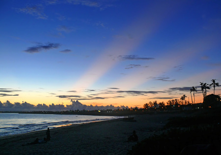 PEMBA, MOZAMBIQUE - 6 DESEMBER 2008: Silhouettes of strange people sitting on the beach. The lights of night city. The sunset in Pemba, Mozambique - 6 December 2008. Indian ocean coast. The beach. The Indian ocean.のeditorial素材