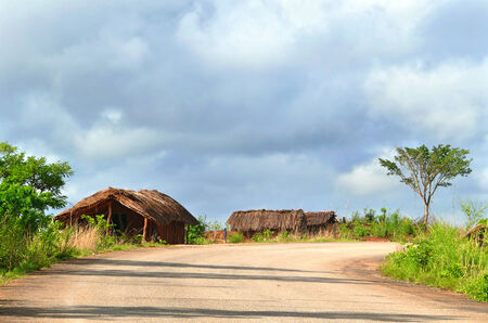 NAIOPUE, MOZAMBIQUE - DECEMBER 7, 2008: the Settlement. A residential building. Unknown African man stands near his home in Naiopue, Mozambique - December 7, 2008. The nature around.のeditorial素材