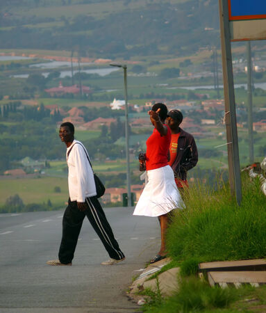 Johannesburg, South Africa - 16 December 2008: Strangers, two men and a woman crossing the road in Johannesburg, South Africa.  Road. City in the background.のeditorial素材