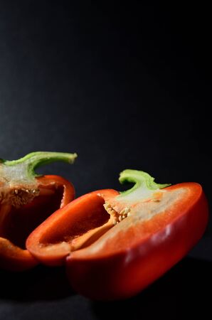 halves of red Bulgarian pepper on a black background vertical orientationの写真素材