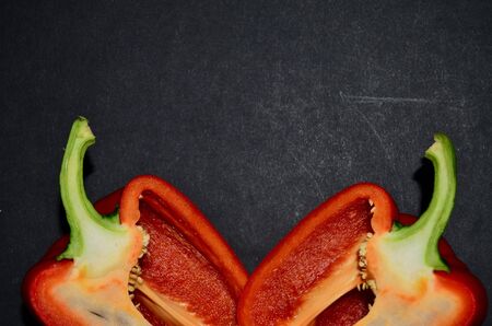 half red Bulgarian pepper on the lower edge view from above on a black background horizontal...