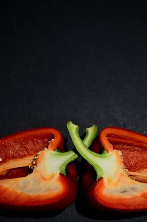 half of the red Bulgarian pepper on the lower edge of the view from above on a black background