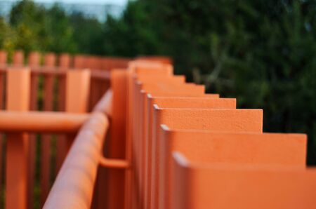 top of orange railings against the background of green trees