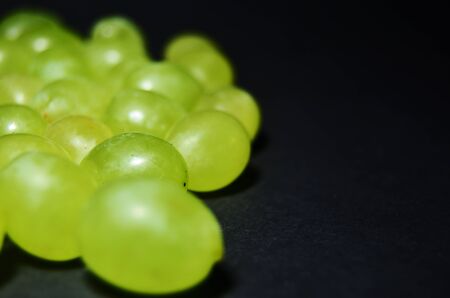 green grape berries on a black background with copy space horizontal orientation