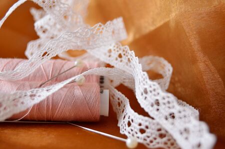 lace thread and needles on brown fabric close-upの写真素材