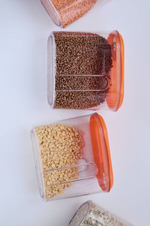 jars of croup of buckwheat peas oatmeal lined up vertically on a white background overlooking the...