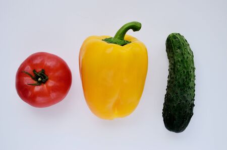 red tomato yellow pepper green cucumber over the top on a white backgroundの写真素材