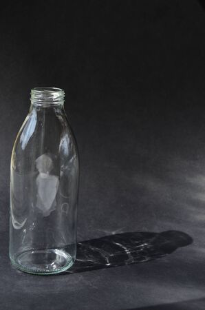 glass bottle on a black background casts the shadow of the game of the sun's raysの写真素材