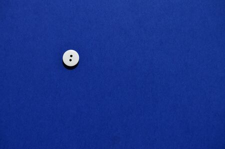 one white wooden button on a blue background in the style of minimalismの写真素材