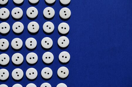 Pattern white wooden buttons on a blue background with a copier spaceの写真素材