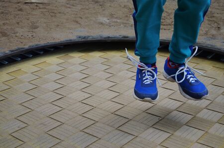 the boy's legs in green pants and blue paints jumped on the trampolineの写真素材