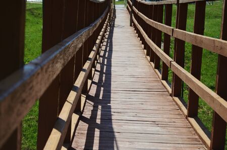 Bridge wooden hanging against the backdrop of green grass on a summer sunny day horizontal...