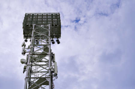 The tower of the spotlight over the football field amid clouds of rain thickened clouds during the matchの写真素材
