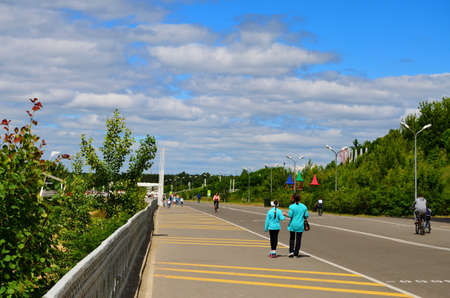 city embankment on which people walk with children and cyclists ride on a summer day on vacation in...