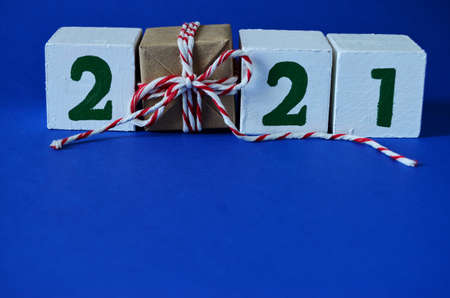 2021 dice and gift instead of one cube in craft paper with a red white bow, laid out on the top edge with a copy space, new year, to give joys, to congratulate on the new year, holiday, Christmas,の写真素材