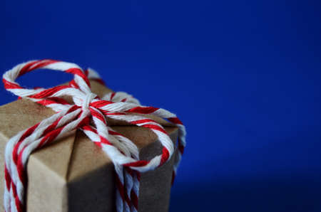 gift with a karsno white bow close-up on a blue background with a copy space, new year, to give...