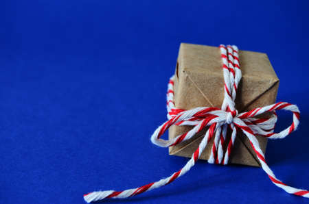 gift in craft paper tied with a red white rope on a blue background close-up with a copy space, new year, to give joys, to congratulate on the new year, holiday, Christmas, Christmas moodの写真素材