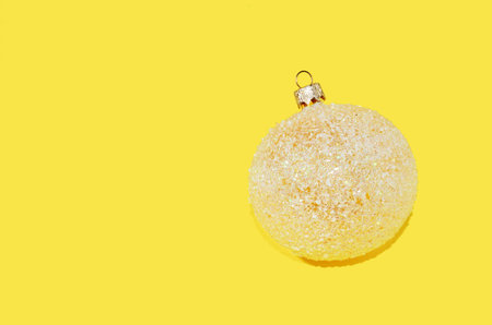 Brilliant Christmas tree ball on a yellow background with copy spaceの写真素材