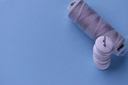 Banner button needle and gray thread on a blue background view from above with copy spaceの写真素材