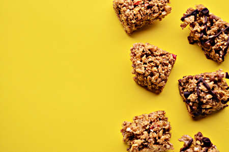 Pieces of granola bar on a yellow background on the right side of the photo view from above with a copy spaceの写真素材