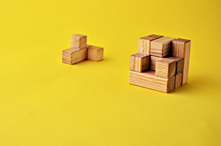 Logical game wooden cube puzzle without one element on a yellow background with a copy space. Solving logical problemsの写真素材