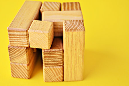A wooden cube of logical play. The cube is not connected to the end. Close up on a yellow background...