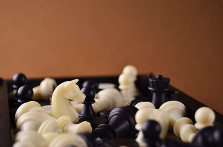 Chess figures of white and black color close-up on a brown background with copy spaceの写真素材