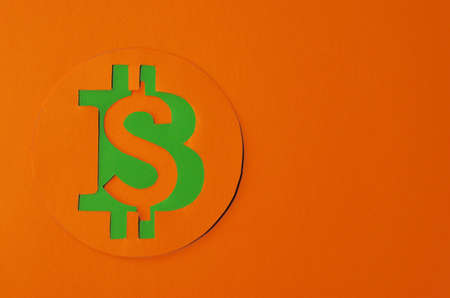 Bitcoin is connected to the dollar on an orange background with a copy space. Conceptual collage about cryptocurrency in the power of minimalismの写真素材